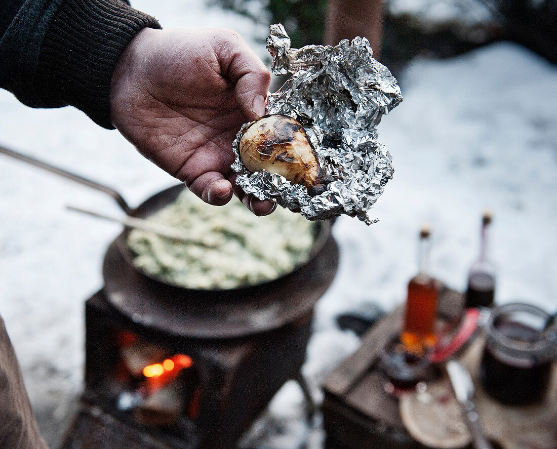 A winter barbecue: a hand holding a baked potato