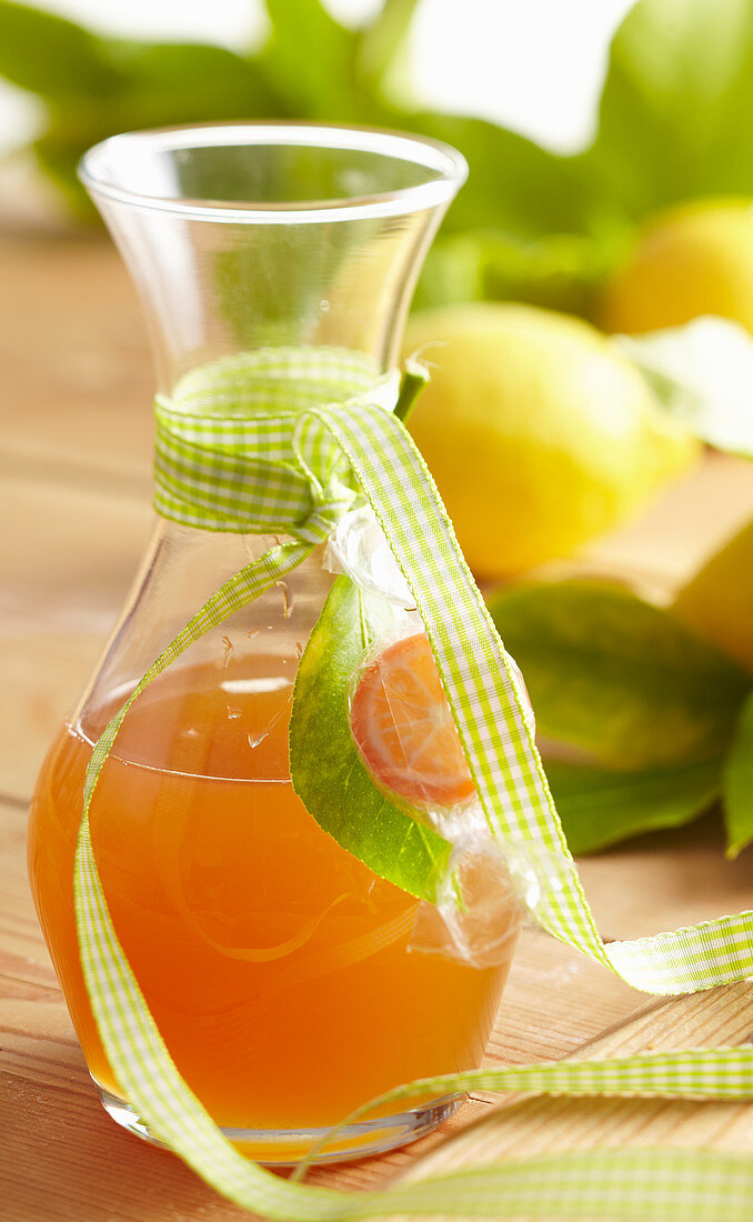 Homemade lemon syrup in a small carafe with a ribbon