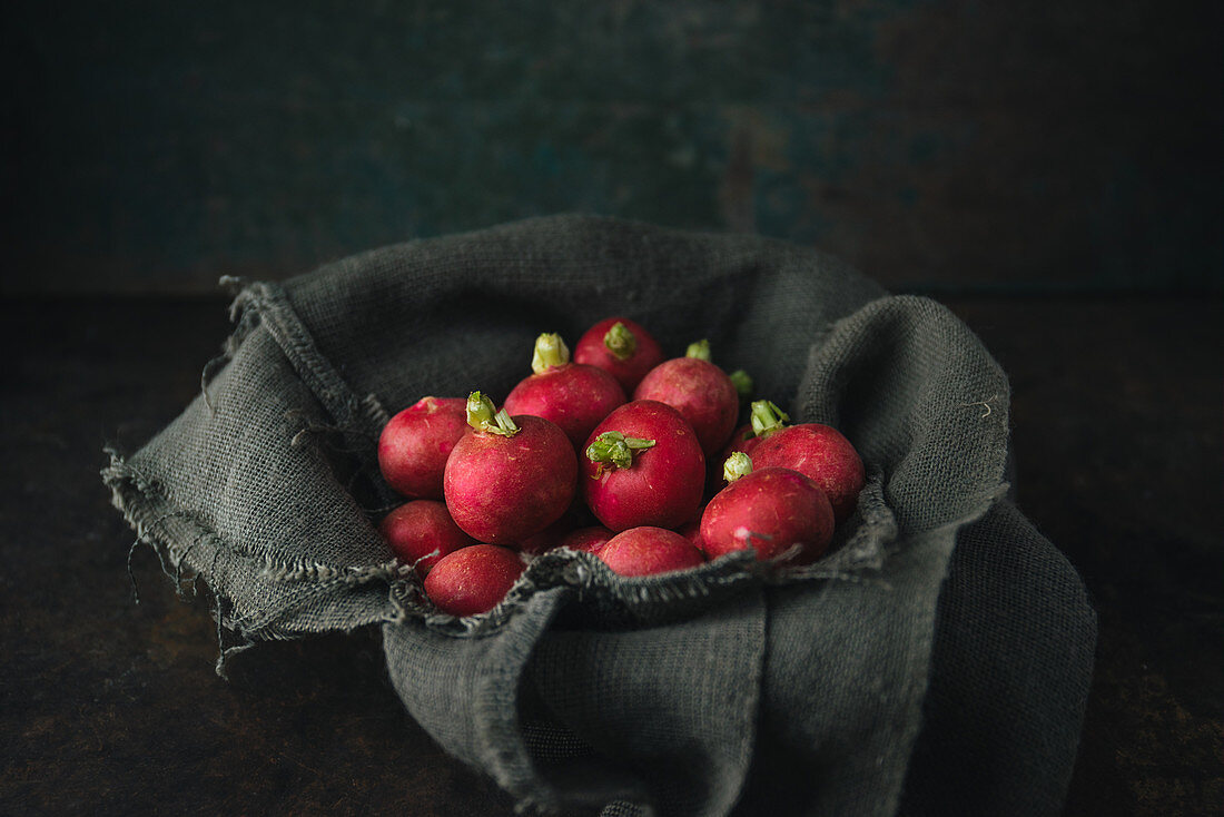 Radishes on a linen cloth in a bowl