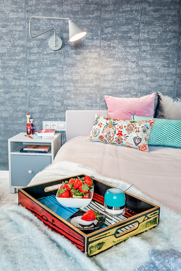 Buntes Tablett mit Erdbeeren auf dem Bett im Schlafzimmer