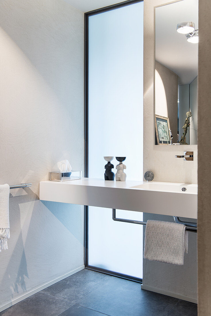 Washstand in front of floor-to-ceiling window in elegant bathroom