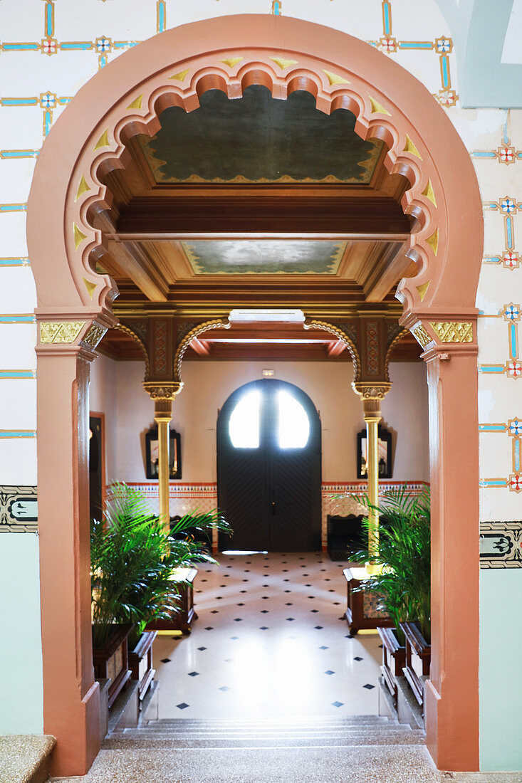 View through ornate, Oriental arched doorway into hall with painted ceiling