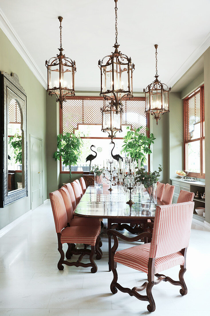 Elegant candlesticks on long dining table and chairs in bright dining room