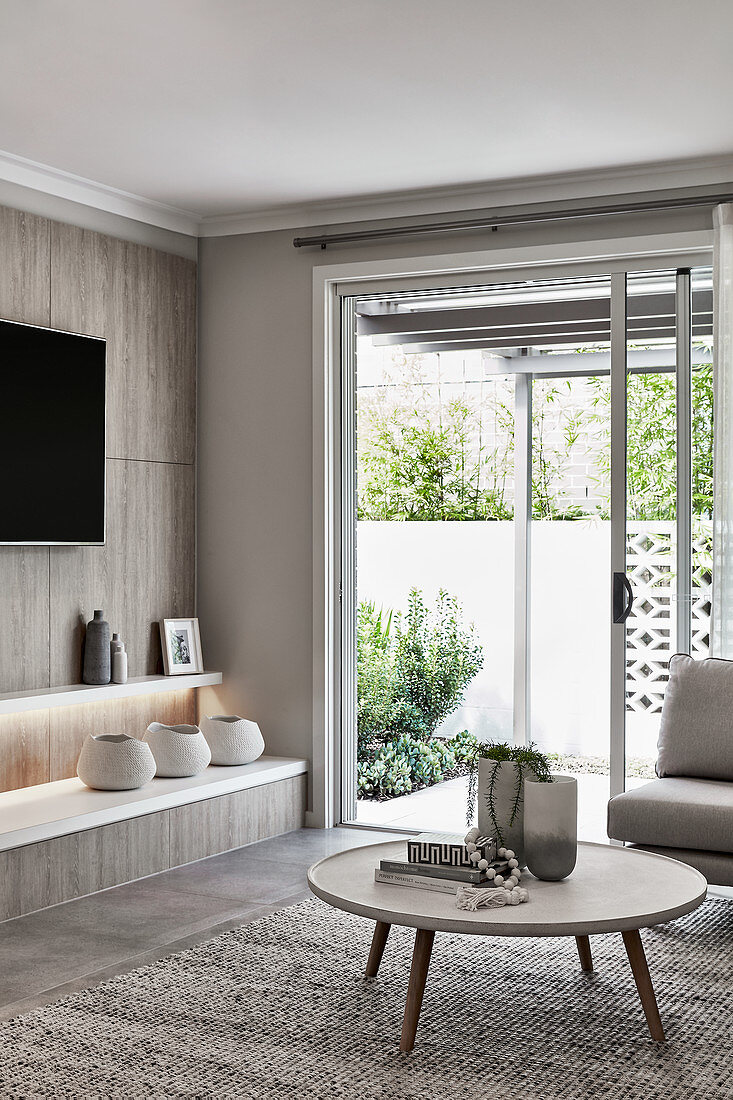 Coffee table, shelves and TV in living room with terrace doors