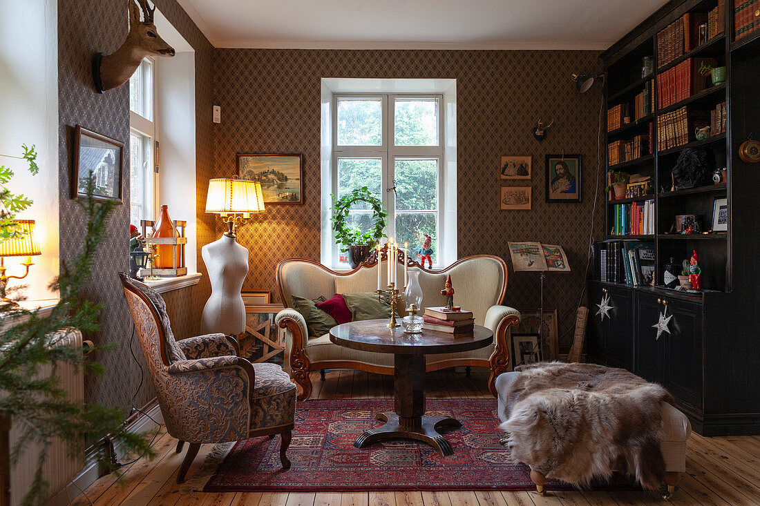 Wohnzimmer mit Antiksofa, elegant gemusterter Wandtapete und Bücherschrank