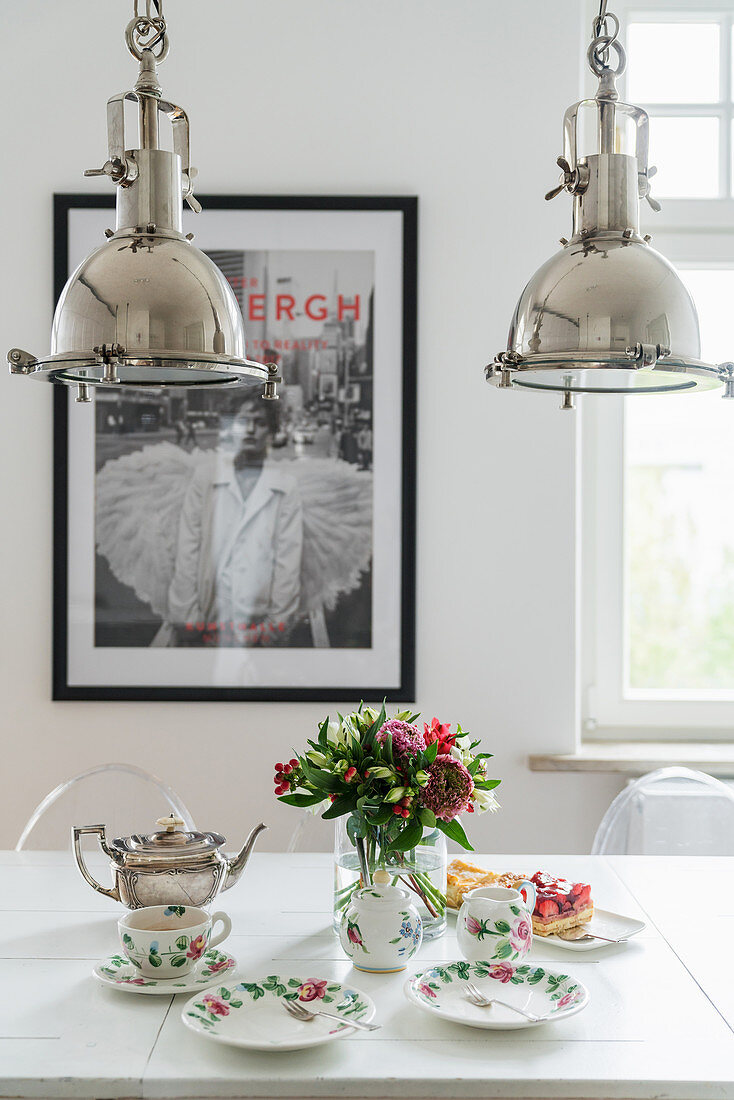 Silver, industrial-style pendant lamps above vintage-style tea set on table
