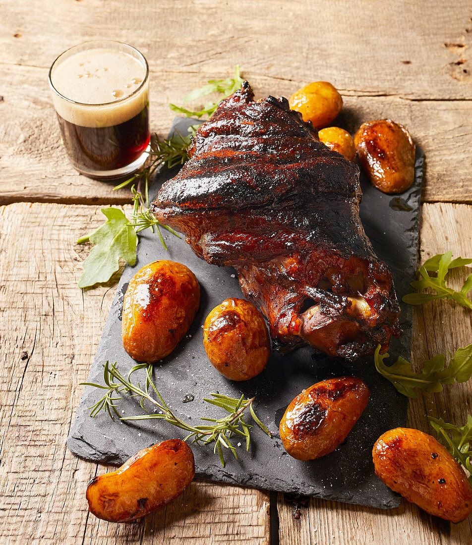 Crispy pork knuckle with baked potato and black beer