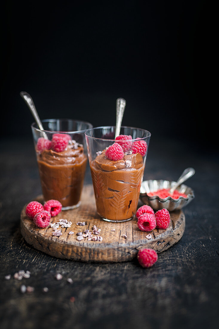 Two glasses of vegan chocolate mousse decorated with fresh raspberries