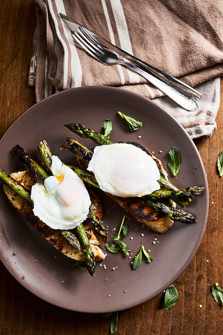 Grilled asparagus with mint leaves and a poached egg on toasted bread