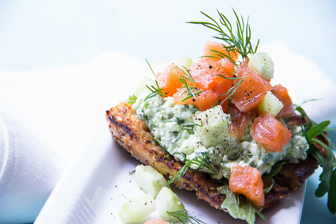 Smoked salmon with cucumber and a herb dip on a wholemeal rösti with dill and rocket