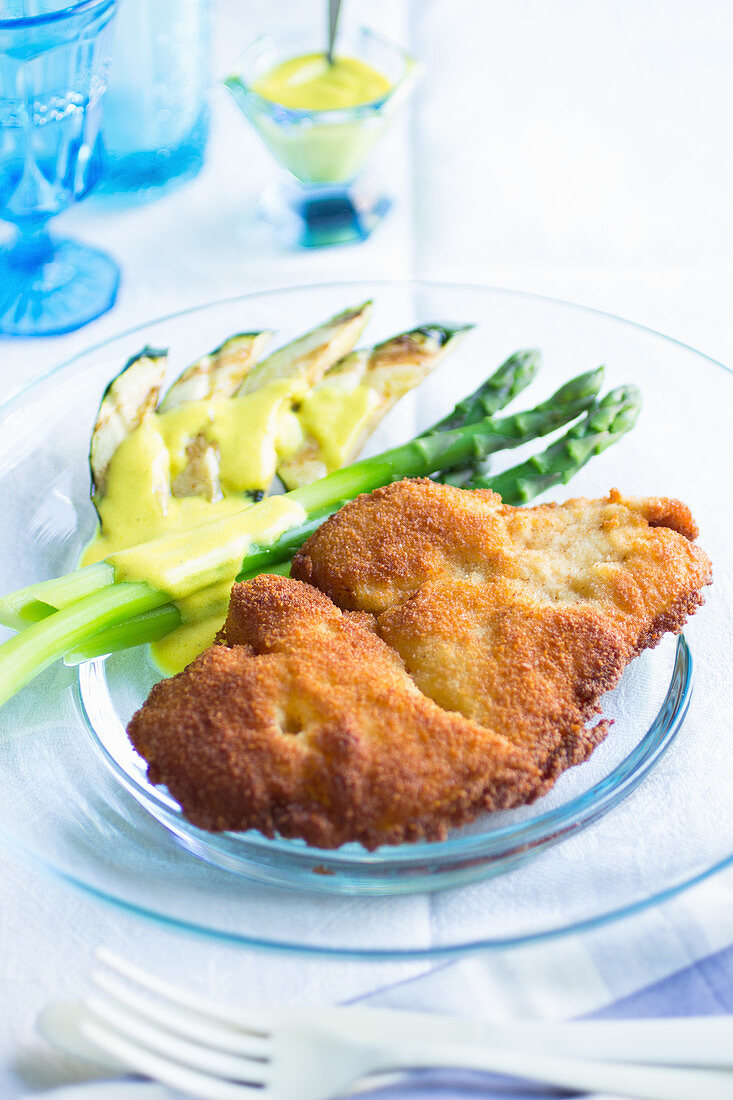 Paniertes Hähnchenfilet mit grünem Spargel und gegrillter Avocado auf Glasteller