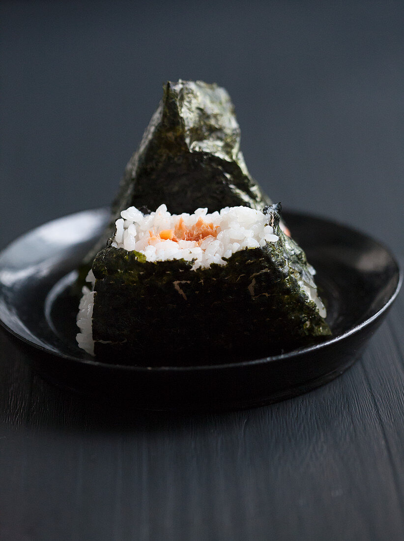 Onigiri gefüllt mit Lachs, eines angebissen (Japan)