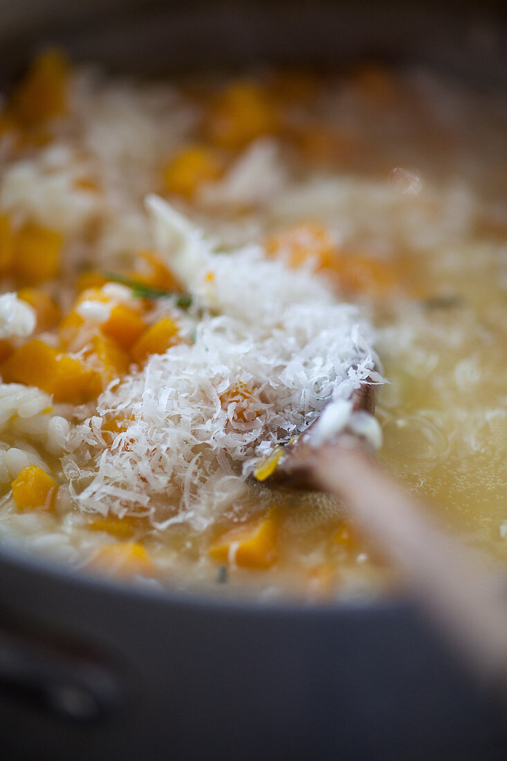 Parmesan cheese being stirred in to pumpkin risotto with orange