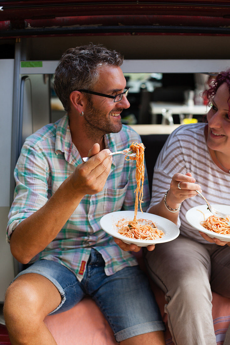 Paar isst Spaghetti vor dem Campingwagen