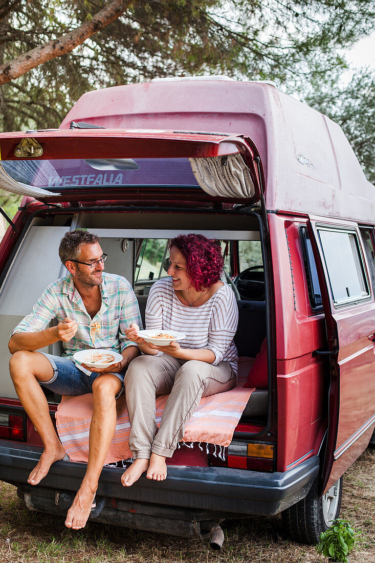 A couple eating spaghetti in a camper van