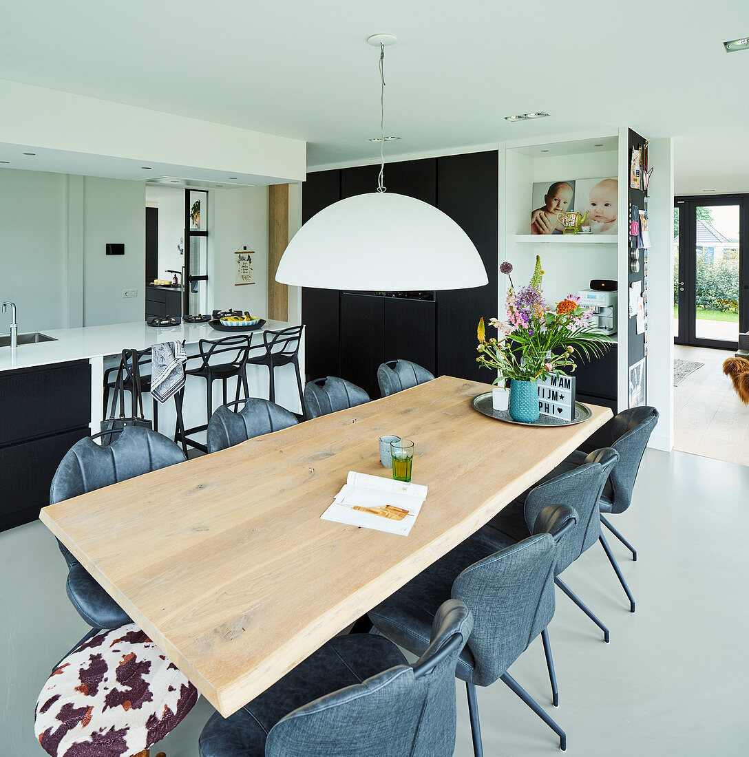 Esstisch aus Eiche in offenem Wohnraum mit schwarz-weißer Küche im Hintergrund