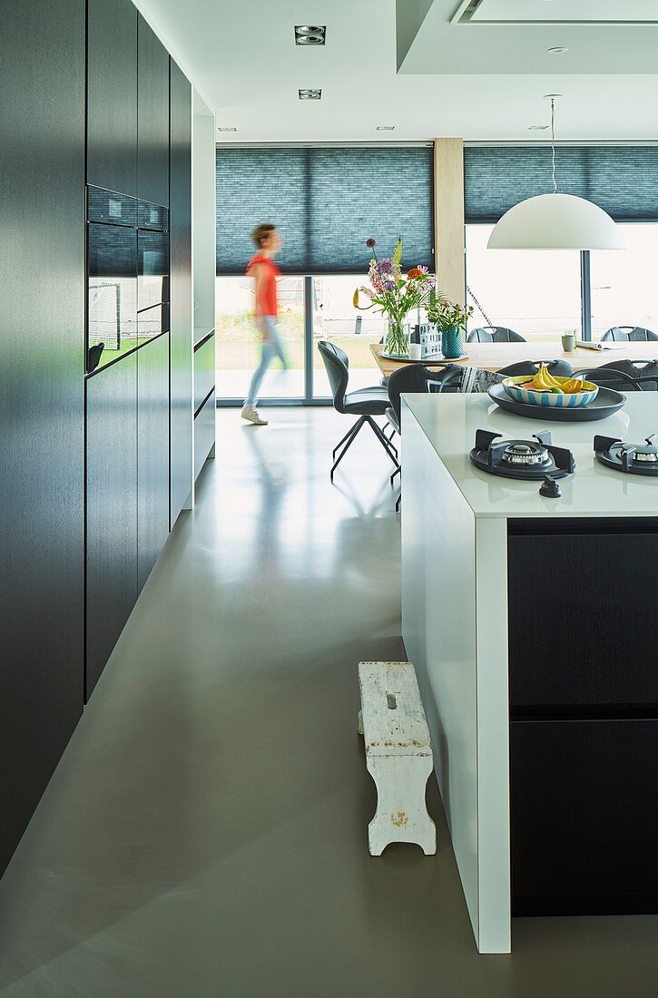 Black cupboards and white high-gloss breakfast bar in open-plan kitchen