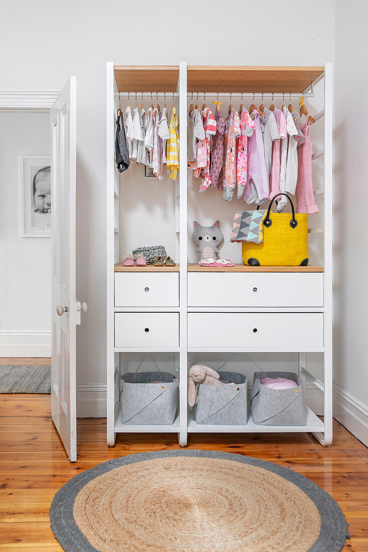 White open wardrobe with baby clothes in children's room