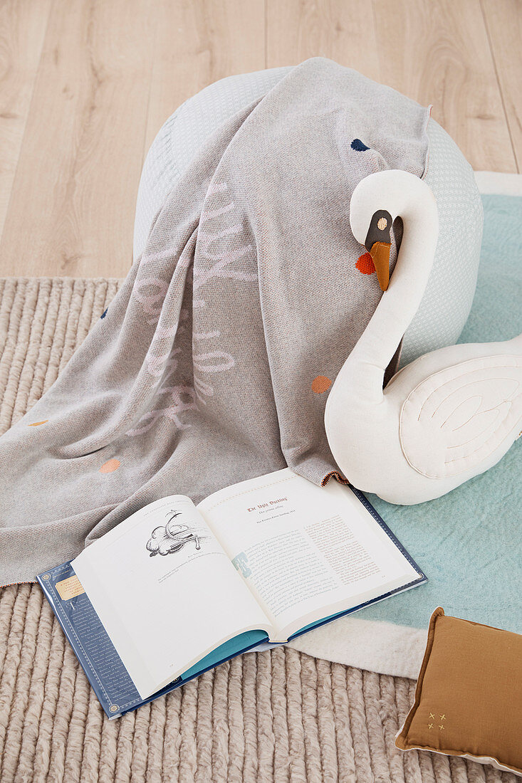 Gray pouf, cozy blanket and swan soft toy in children's room