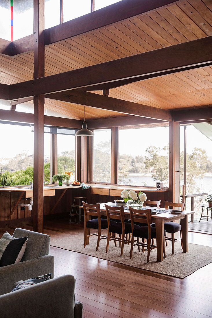 Open living room with wide window fronts and dining area under a wooden ceiling