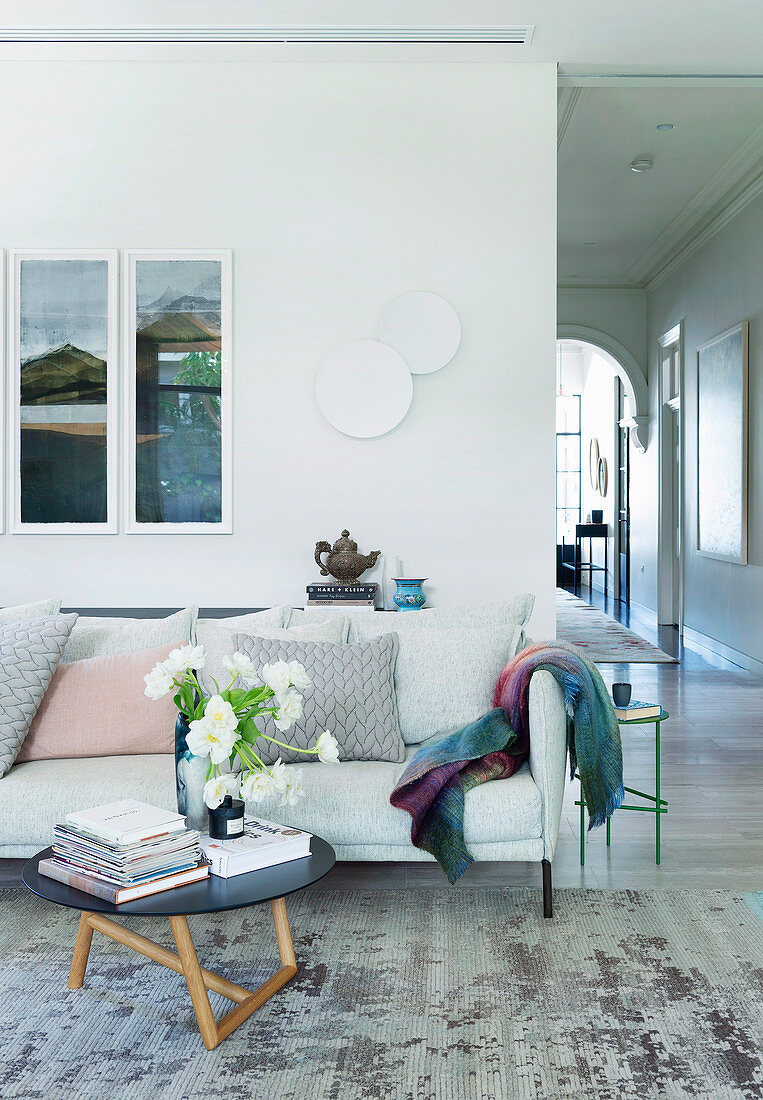 Light gray upholstered couch with coffee table next to hallway