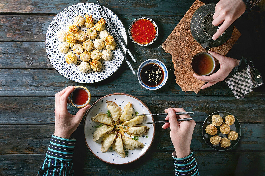 Dinner with Dim sum Gyozas asian fried dumplings set, variety of sauces, tea cups and teapot