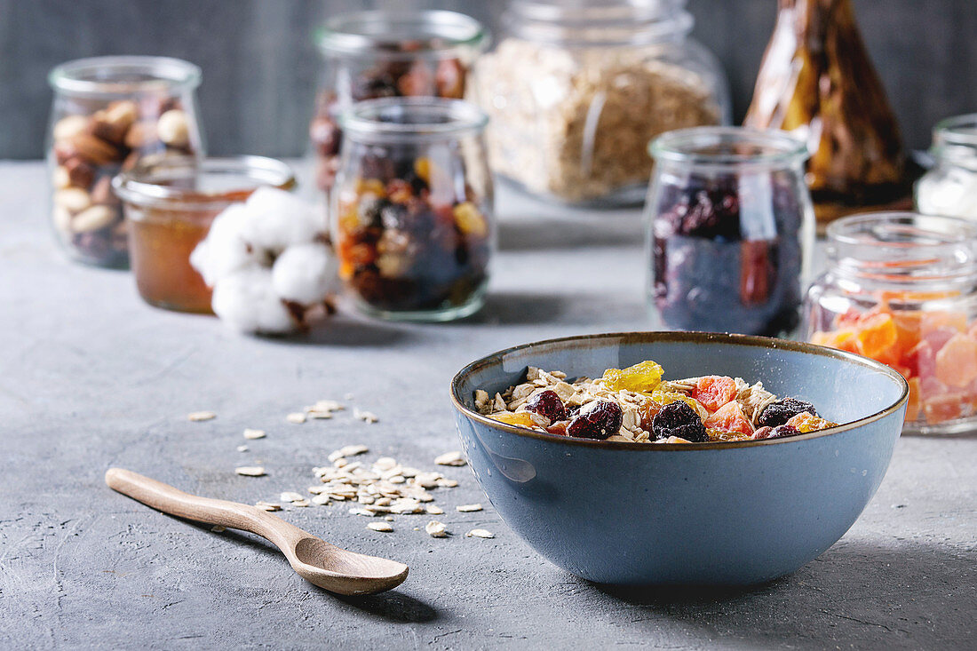 Selbstgemachtes Müsli mit Trockenfrüchten, dahinter Zutaten