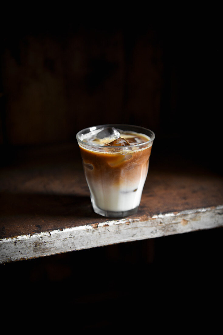 An iced latte in a glass against a dark background