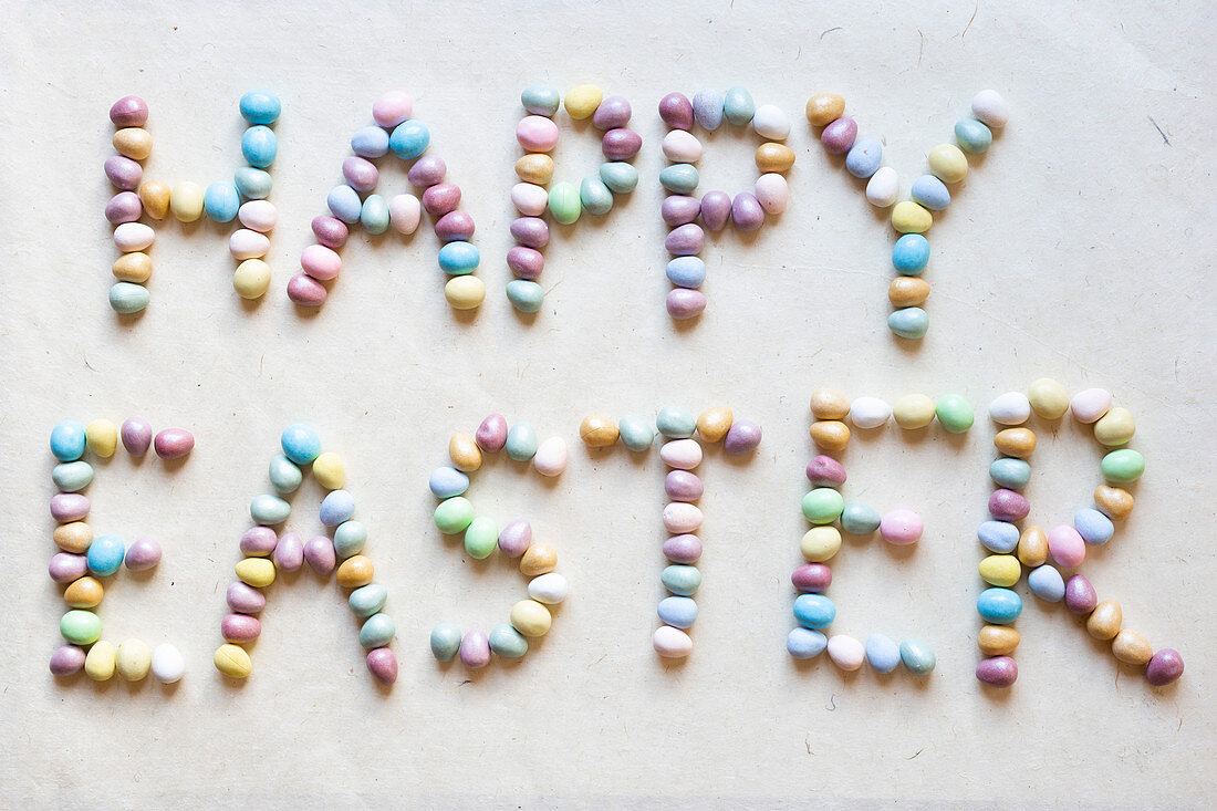 Schriftzug 'Happy Easter' aus bunten Schokoladenostereiern gelegt