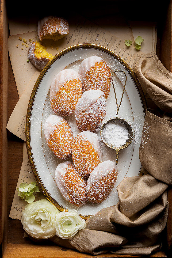 Gluten-free lemon madeleines with icing sugar on a platter