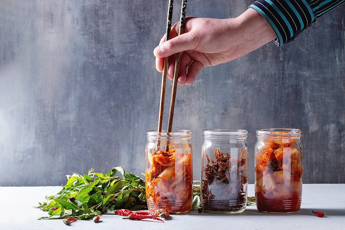 Korean traditional fermented appetizer kimchi cabbage and radish salad, fish snack served in glass jars