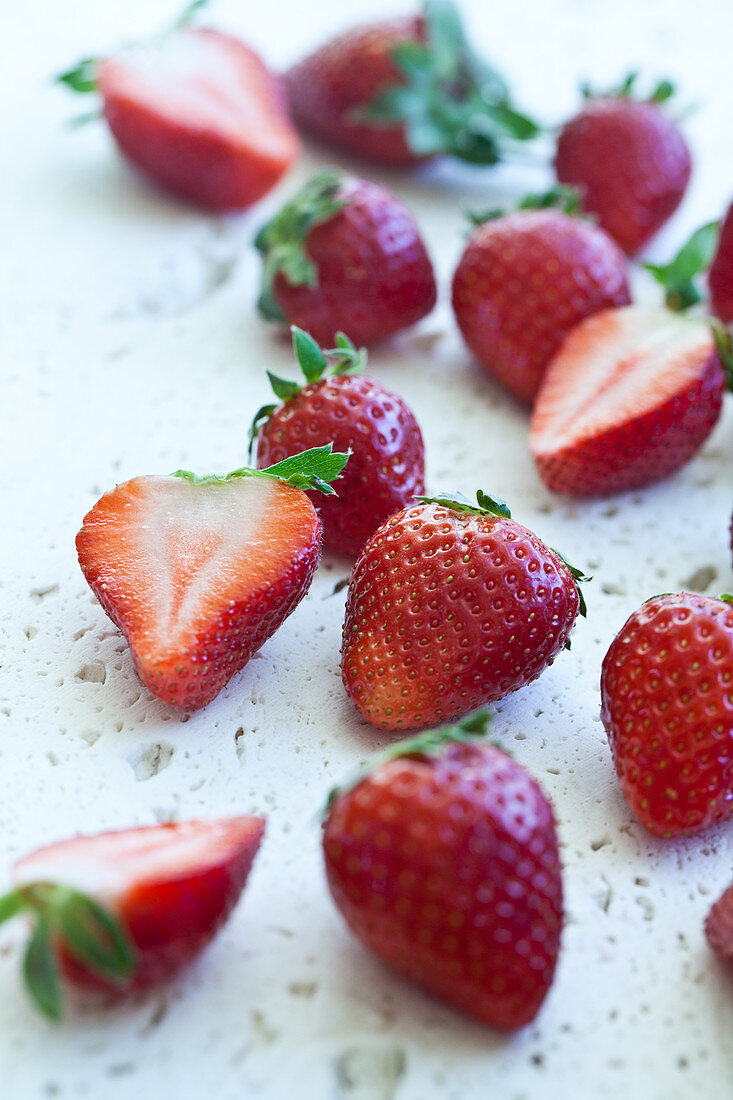 Strawberries, whole and halved, photographed from above on a white textured surface