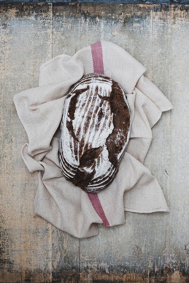 A freshly baked loaf of brown bread on tea towel