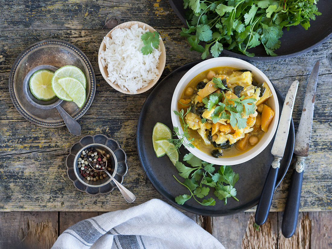 Plate with delicious vegetarian curry and lime slices placed on tray on wooden background
