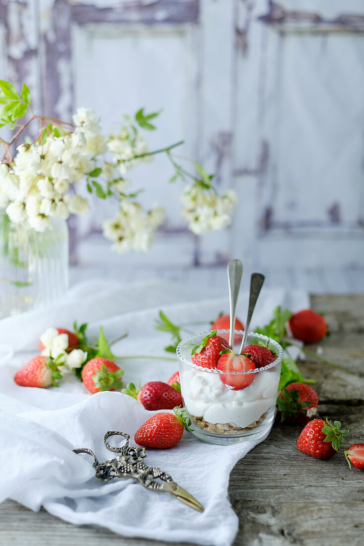 Creamy sweet dessert with fresh juicy tasty strawberries served inside a glass on a rustic wooden table