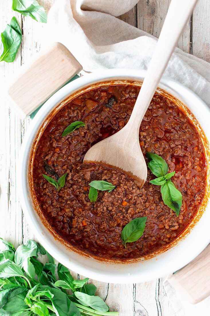 Bolognese Sauce mit Basilikum in weissem Topf