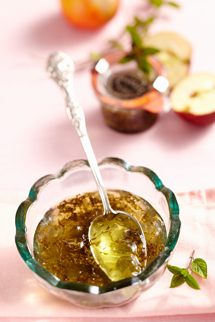 Mint and apple jelly in a glass bowl with a silver spoon