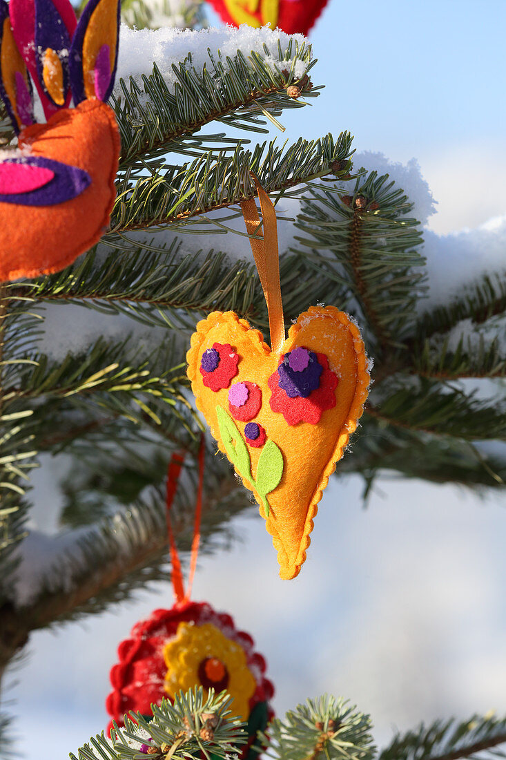 Schneebedeckter Tannenbaum mit selbstgemachten Filzanhängern