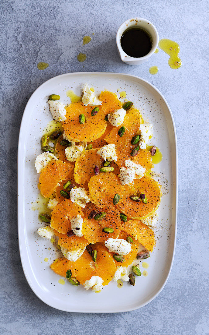Orange, bocconcini and pistachio salad with a jug of spicy dressing
