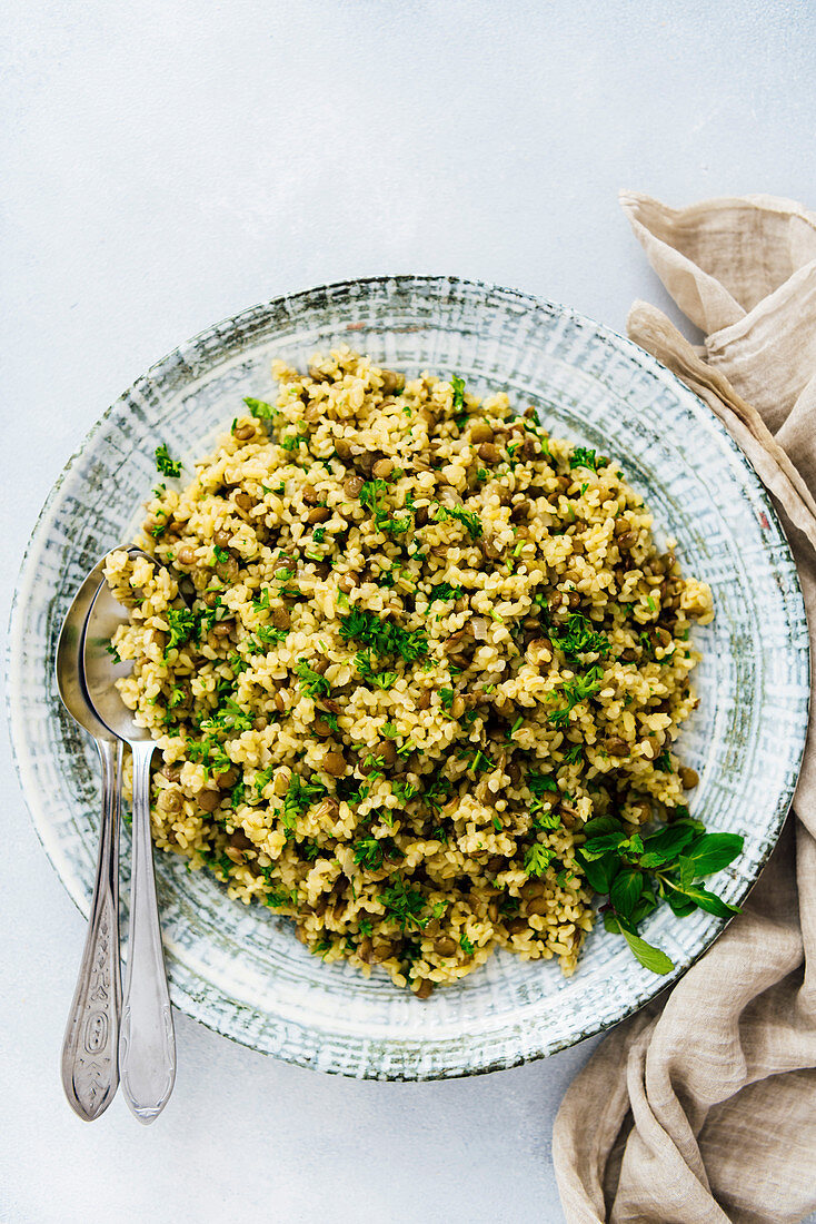 Bulgur pilaf with green lentils and herbs served in a large ceramic bowl