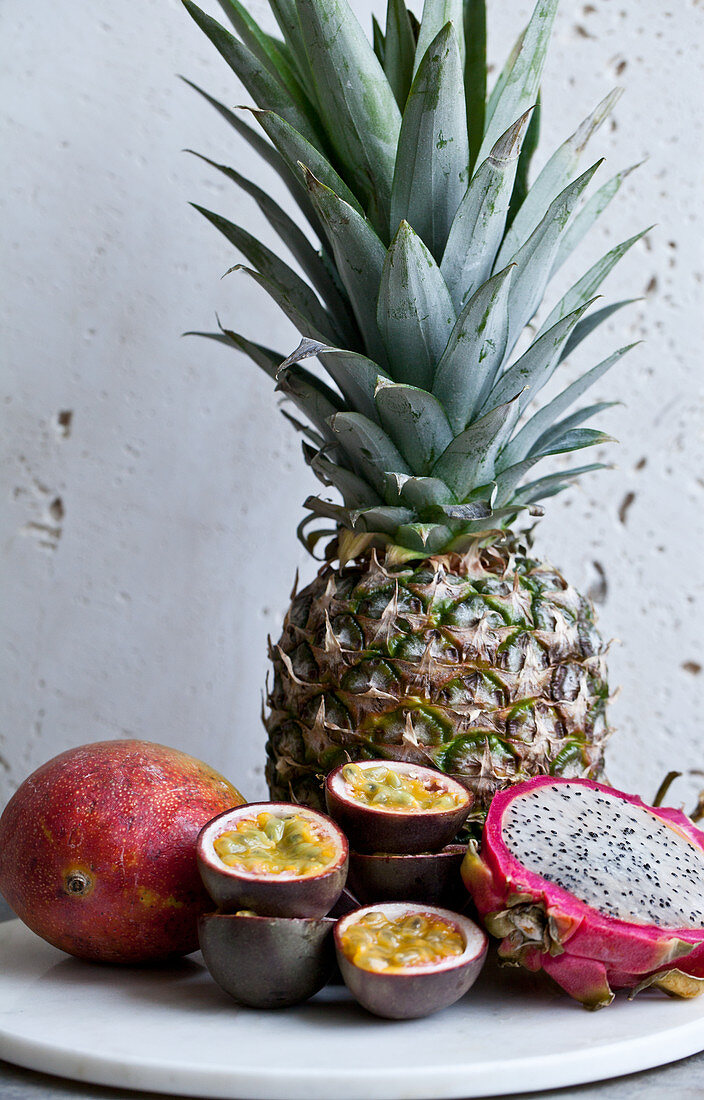 Pineapple, passion fruit halves, dragonfruit and mango with a white background