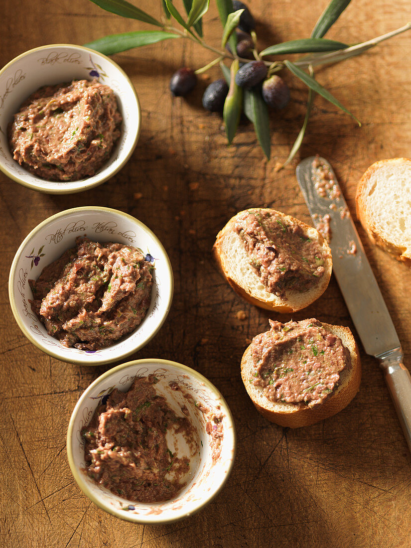 Tapenade in Schälchen und auf Baguette