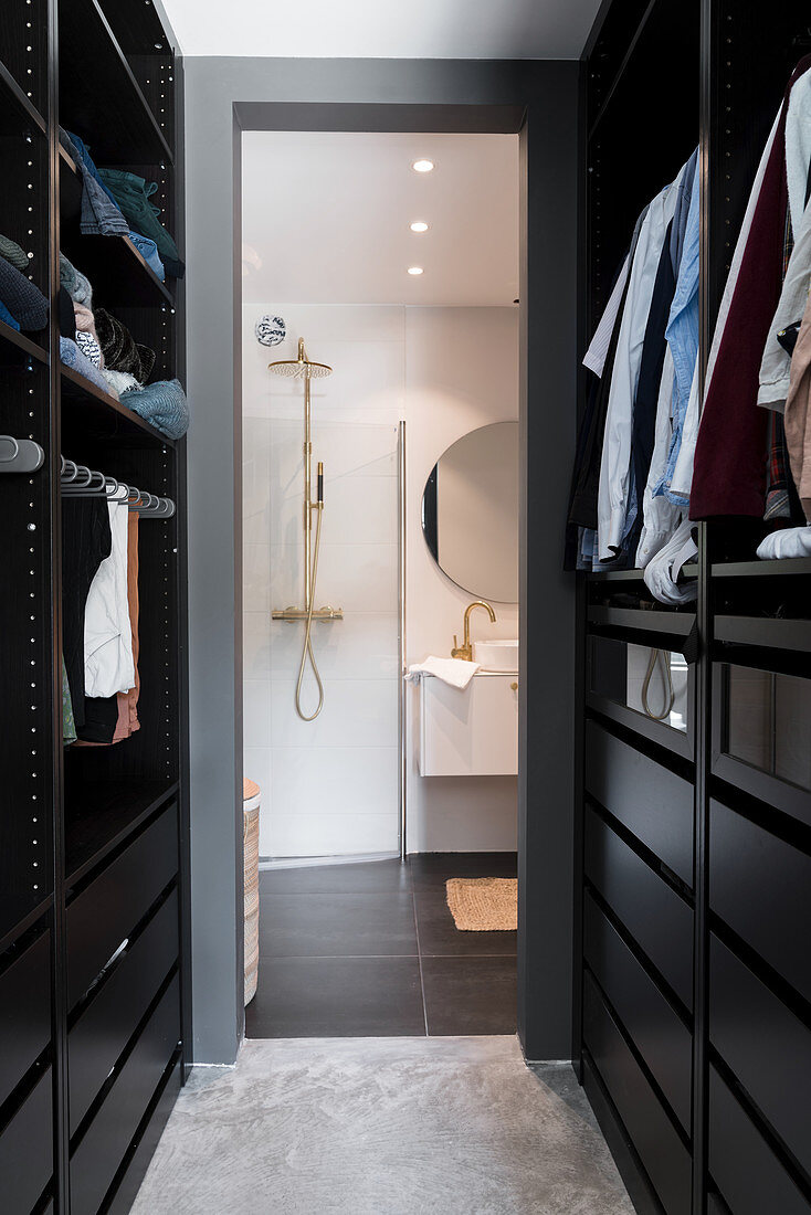 View through walk-in wardrobe into modern bathroom with shower and washstand