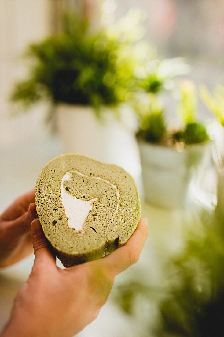 Hand holding slice of delicious matcha roll