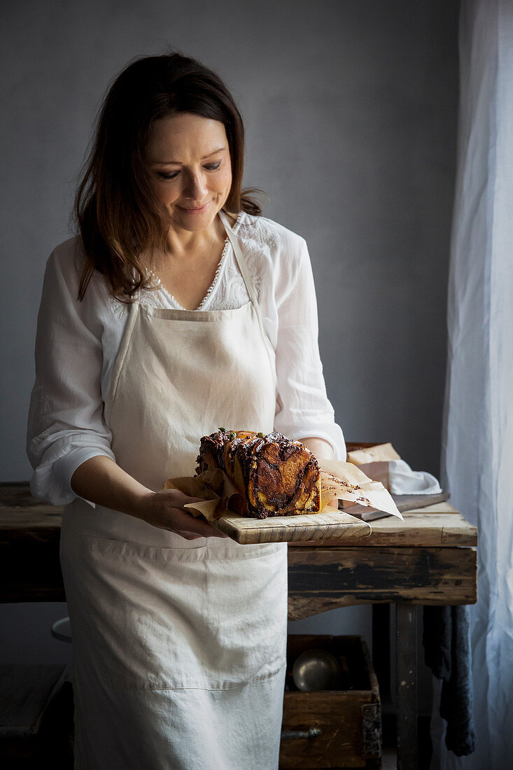 Woman serving chocolate, tahini and halva babka with cardamom syrup