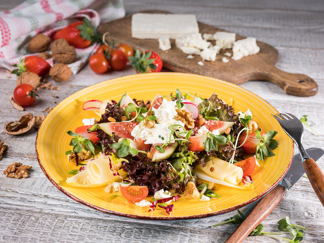 Fitness salad with figs, cheese, cherry tomatoes, walnuts and strawberries