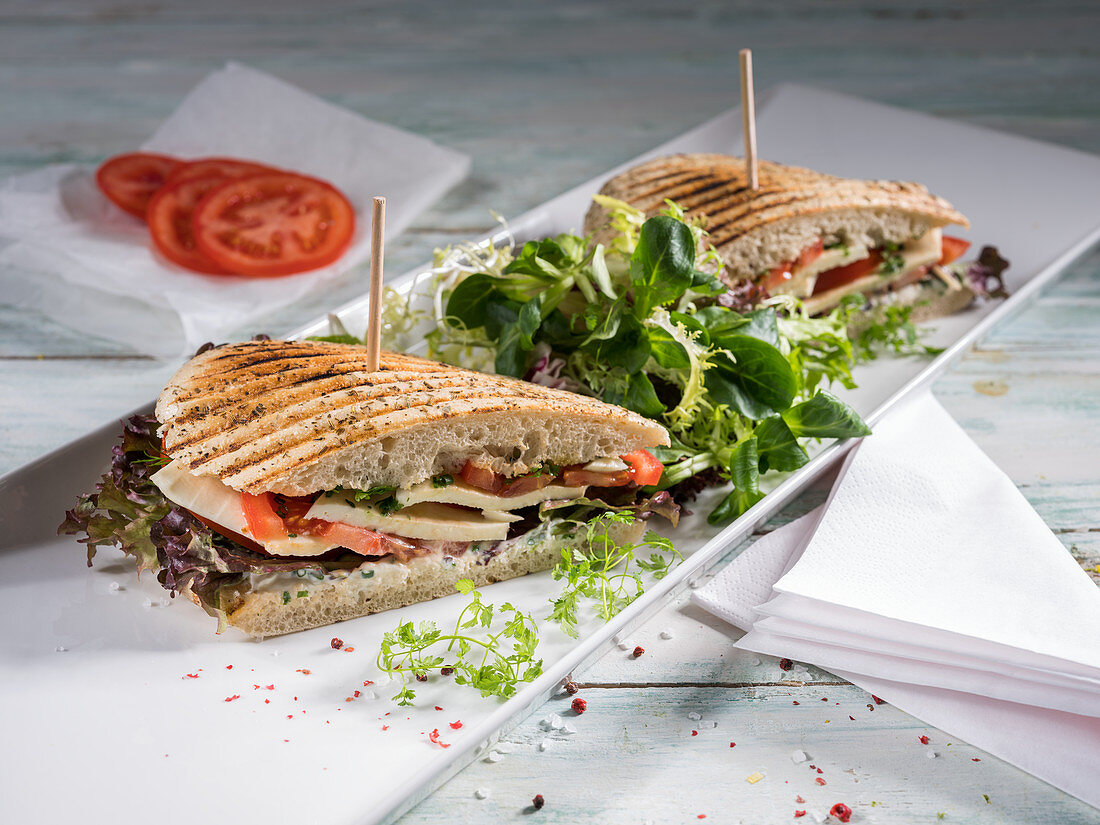 A grilled panini with tomato, mozzarella, lettuce and chervil