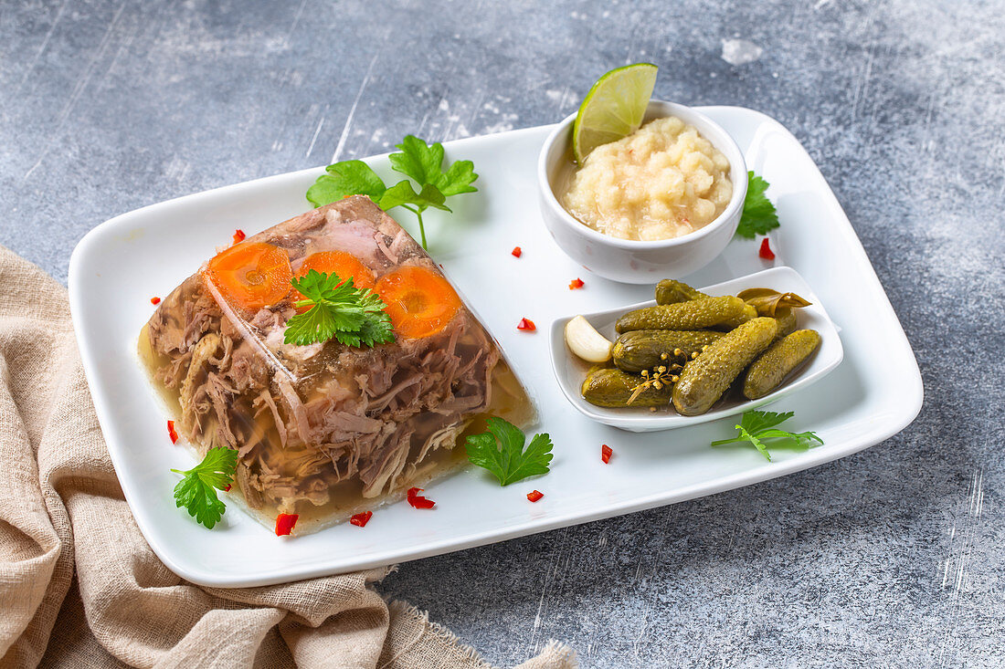 Aspic with pickled gherkin and horseradish sauce. Kholodets is a jellied meat dish of traditional Russian cuisine.