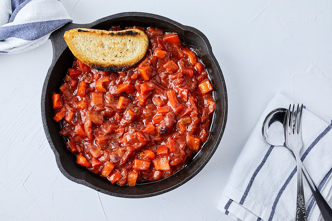 Tomatensalsa in Gußeisenpfanne und Scheibe Röstbrot