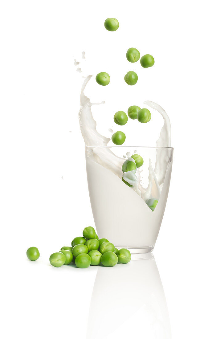 Peas falling into a glass of milk